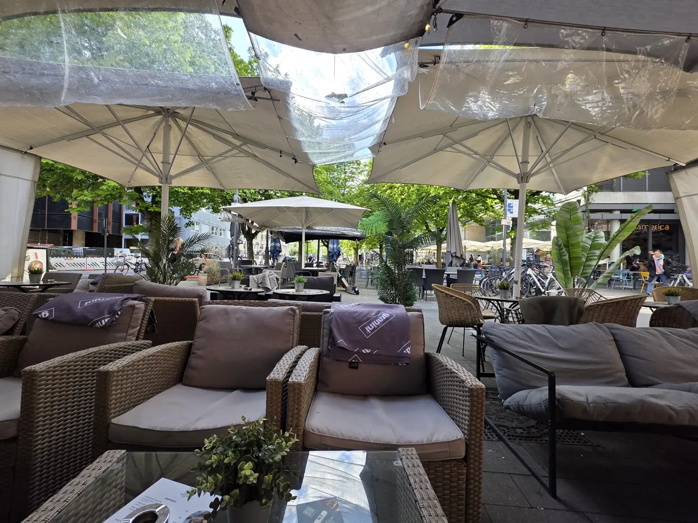Loungebereich draußen unter großen Sonnenschirmen mit Rattansofas und Kissen bei Tageslicht