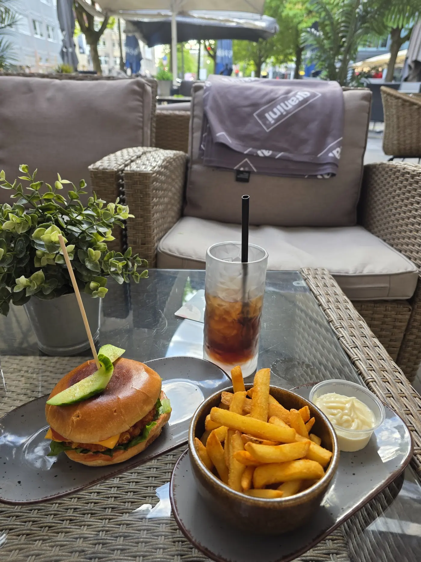Burger mit Pommes und ein Longdrink auf einem Tisch der Terrasse